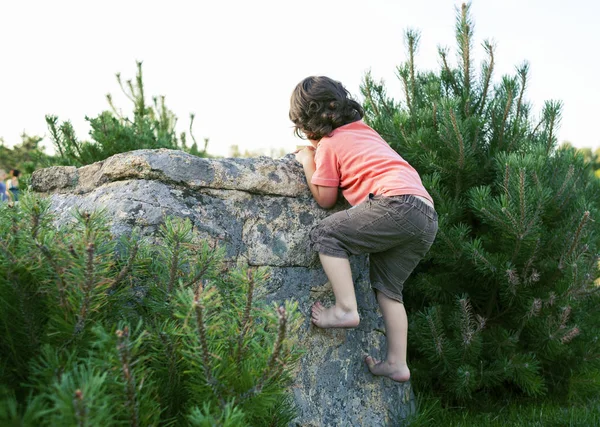 Pojken klättrar på stenen. — Stockfoto