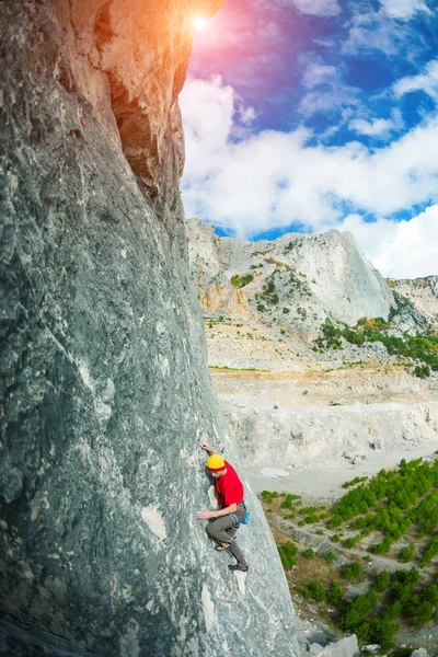 Um alpinista com um chapéu numa rocha . — Fotografia de Stock