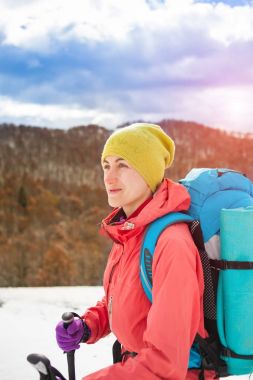 Dağlarda kar üzerinde yürüyen sırt çantası ile kız.