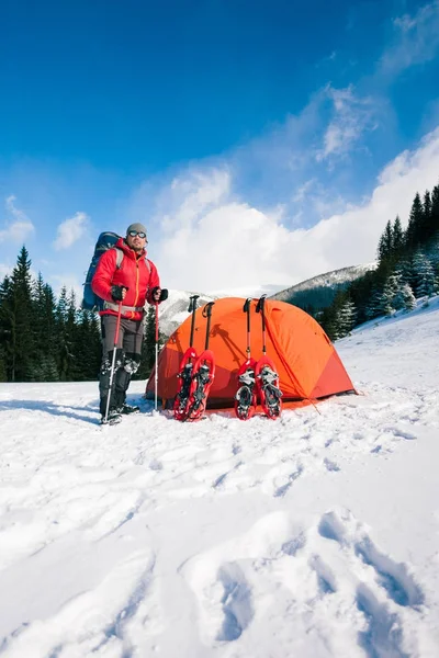 Wspinacz w pobliżu namiotu z rakiety śnieżne. — Zdjęcie stockowe