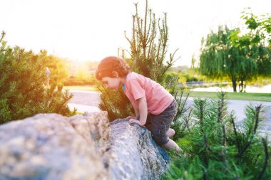 Çocuk taşa tırmanıyor.