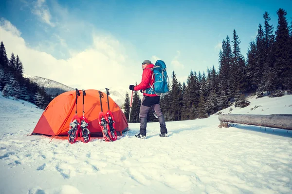 Escalador perto da tenda com sapatos de neve . — Fotografia de Stock