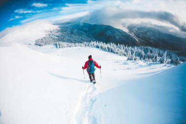 Bir erkekte kışın dağlarda kar ayakkabıları. 