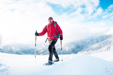 Bir erkekte kışın dağlarda kar ayakkabıları. 