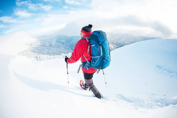 Un hombre en raquetas de nieve en las montañas en el invierno . — Foto de Stock