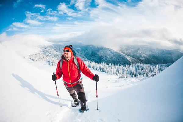 Een man in sneeuwschoenen in de bergen. — Stockfoto