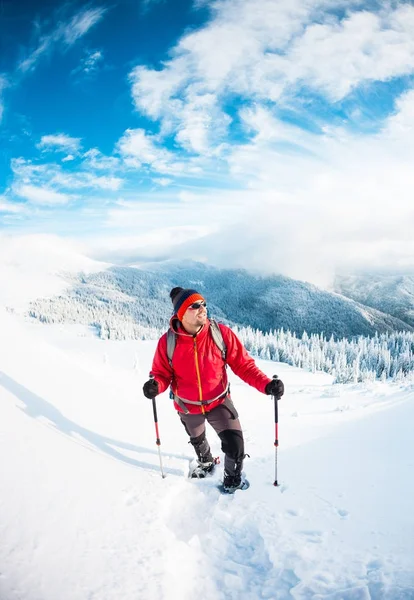Een man in sneeuwschoenen in de bergen in de winter. — Stockfoto