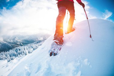 Bir erkekte kışın dağlarda kar ayakkabıları. 