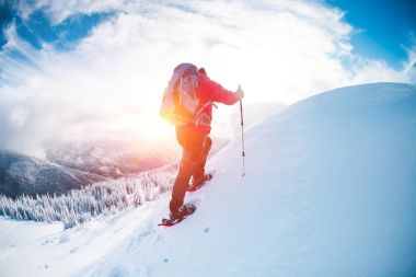 Bir erkekte kışın dağlarda kar ayakkabıları. 