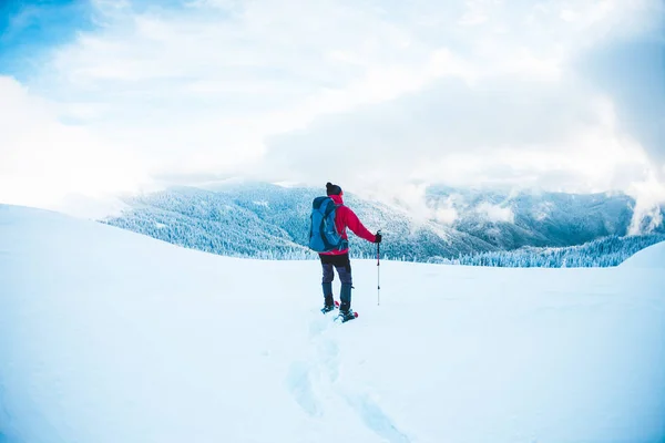 Un hombre en raquetas de nieve en las montañas . — Foto de Stock