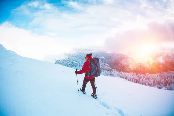 Un hombre en raquetas de nieve en las montañas . — Foto de Stock