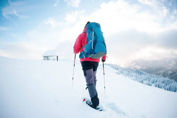 Um homem de sapatos de neve nas montanhas no inverno . — Fotografia de Stock