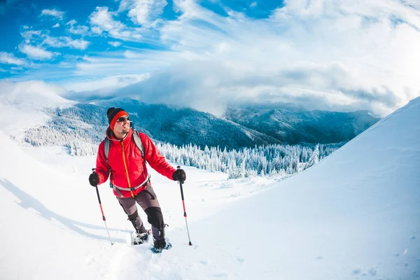 Un hombre en raquetas de nieve en las montañas . — Foto de Stock