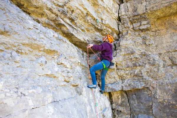 Kvinnan i hjälmen klättrar rock. — Stockfoto