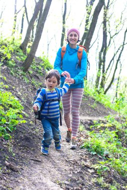 Çocuk ve annesi ormana doğru yürüyor.