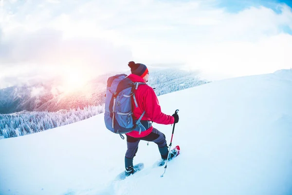 Un hombre en raquetas de nieve en las montañas . — Foto de Stock