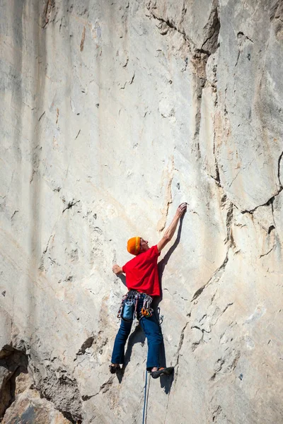 Un hombre está entrenando para trepar sobre una roca . — Foto de Stock