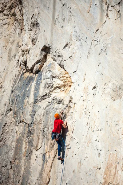 Un hombre está entrenando para trepar sobre una roca . — Foto de Stock