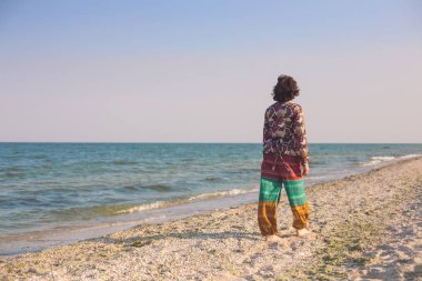 Bir kız sahilde yürüyor.