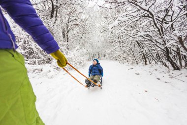 Bir kadın bir çocuk bir kızağa taşıyor.