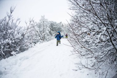 Çocuk kar üzerinden çalışır.