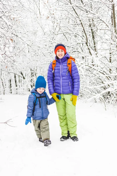 Μαμά βόλτες με τον γιο της πάνω από το χιονισμένο δάσος. — Φωτογραφία Αρχείου