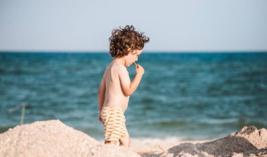 Çocuk kumlu plaj boyunca yürür.