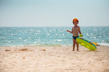 Çocuk sahilde yürüyor.