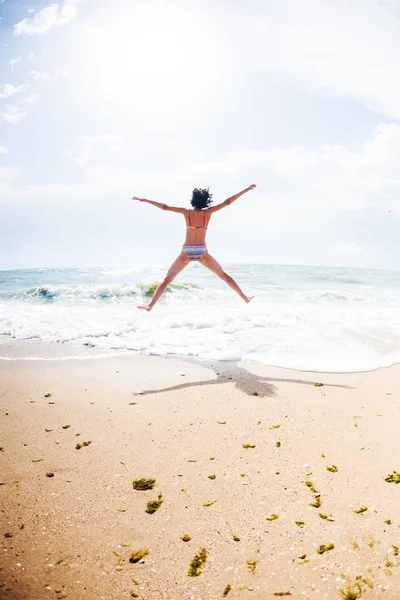 Uma menina está pulando na praia . — Fotografia de Stock