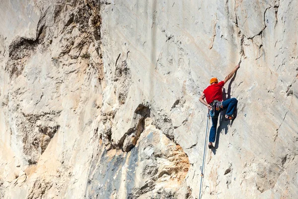 Un hombre está entrenando para trepar sobre una roca . — Foto de Stock