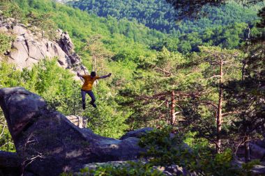 Bir adam bir dağın tepesinde atlıyor.