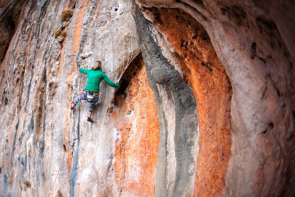A woman climbs the rock.