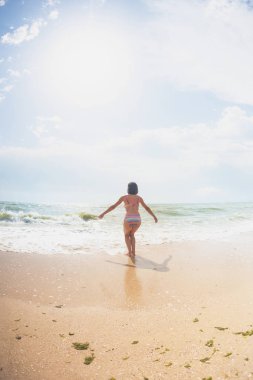 Bir kız sahilde atlıyor.