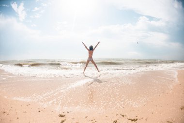 Bir kız sahilde atlıyor.