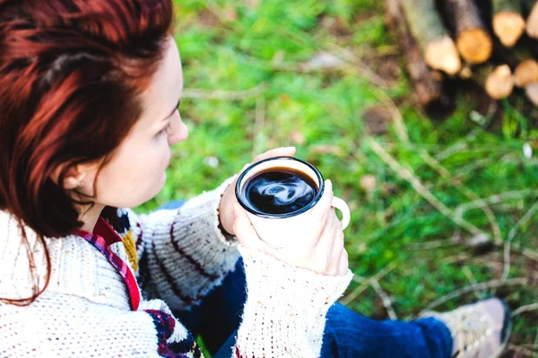 Una chica está bebiendo café junto al fuego . — Foto de Stock