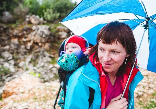 Une femme porte un enfant dans un sac à dos . — Photo