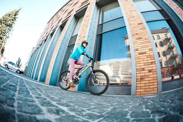 Chica está montando una bicicleta por la ciudad . —  Fotos de Stock