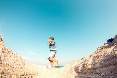 Çocuk kumlu plaj boyunca yürür.