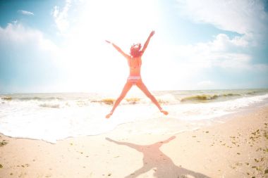 Bir kız sahilde atlıyor.