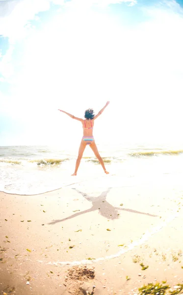 Een meisje is springen op het strand. — Stockfoto