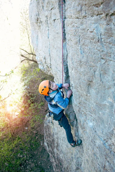 Kid escalador de rocha sobe o penhasco . — Fotografia de Stock