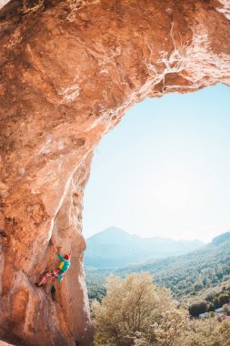 Bir dağcı kaya tırmanıyor.