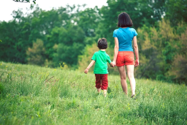 El niño camina con su madre en el prado . — Foto de Stock