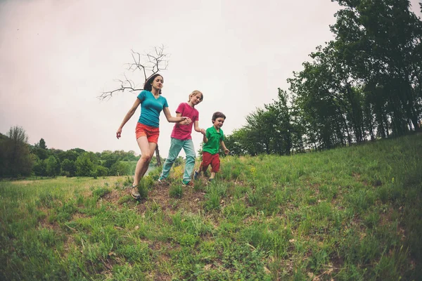 Una mujer con hijos corre por la hierba . —  Fotos de Stock