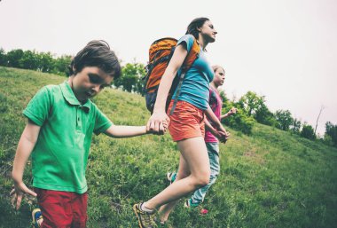 Çocuklu bir kadınla hiking gider. Kadın kollarından oğulları aldı. Aile ile seyahat. Çocuk ile kardeşi ve annesi ormanda yürür. Sırt çantaları ile yürüyüş. Balık gözü lens