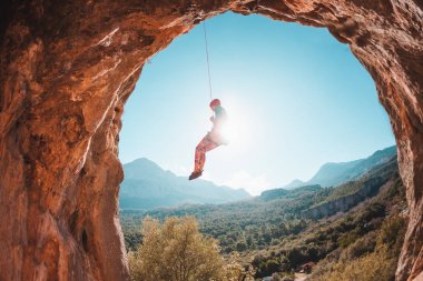 Dağcı güzel dağlar zemin karşı bir ip üzerinde asılı. Kızı aşağı gider. Türkiye'de dağcılık. Dağ manzarası. Temiz havada egzersiz. Rock bir kemer şeklinde. Mağara.