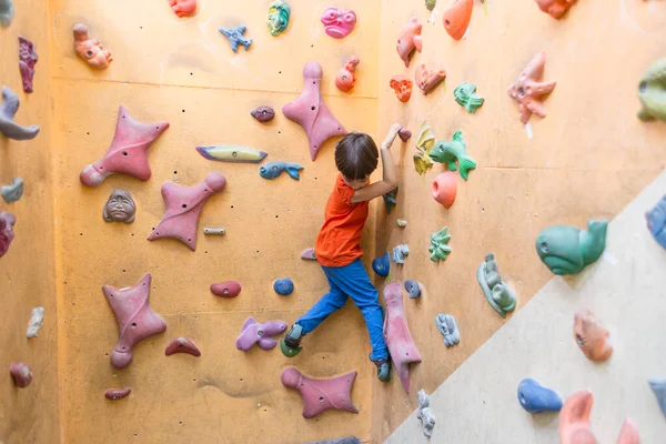 Niño escalando en la pared de rocas artificiales en el gimnasio — Foto de Stock