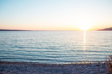 Deniz ve gökyüzü bulutlu gün batımında.