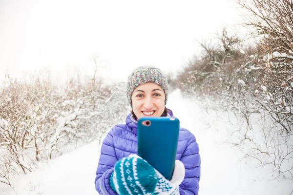 Kobieta robi zdjęcie na telefon komórkowy w lesie zimowym. — Zdjęcie stockowe