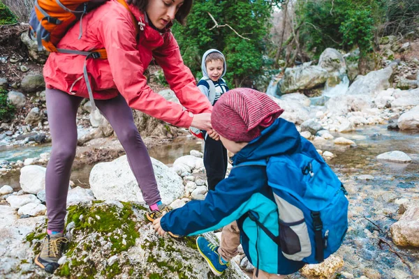 Жінка допомагає дитині перетнути гірську річку . — стокове фото